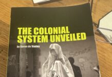 The Colonial System Unveiled **Alt text:** Cover of the book *The Colonial System Unveiled* by Baron de Vastey, translated and edited by Chris Bongie. The cover features a striking black-and-white photo of a person draped in a white shroud-like garment, holding a painted mask resembling a skull. The background shows a group of similarly dressed figures and a wall with the word "Senate" faintly visible. The title appears in bold yellow-green text at the top.