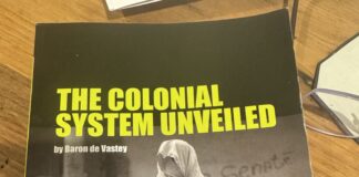 The Colonial System Unveiled **Alt text:** Cover of the book *The Colonial System Unveiled* by Baron de Vastey, translated and edited by Chris Bongie. The cover features a striking black-and-white photo of a person draped in a white shroud-like garment, holding a painted mask resembling a skull. The background shows a group of similarly dressed figures and a wall with the word "Senate" faintly visible. The title appears in bold yellow-green text at the top.